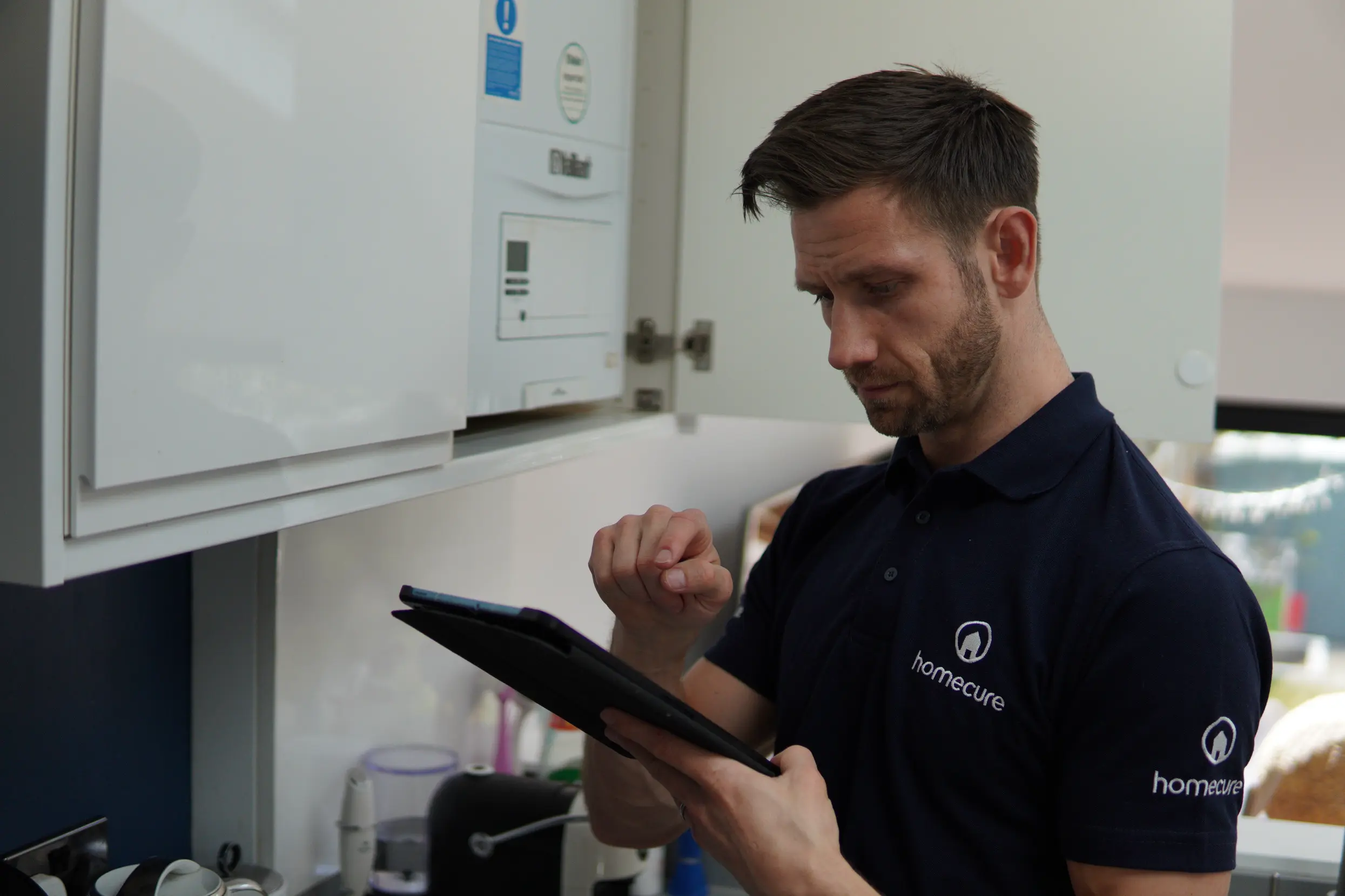 An employee holding a tablet while servicing the boiler