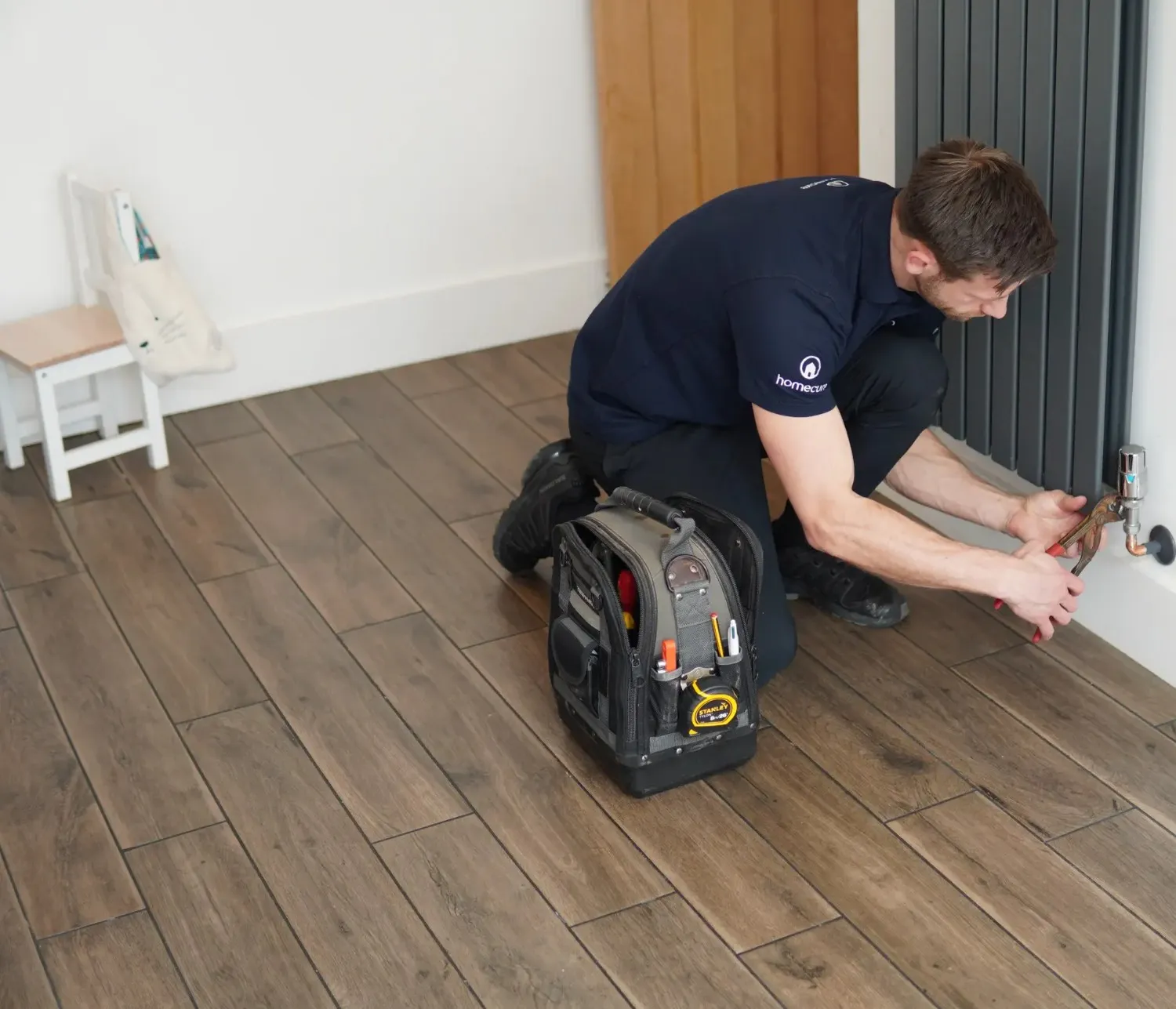 A Homecure Heating Engineer carrying out repairs on a radiator in Chiswick